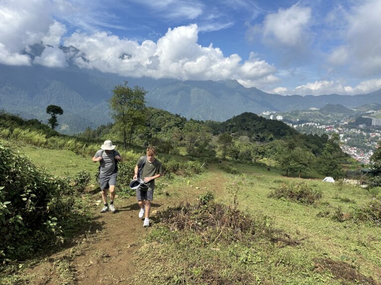 Hmong guide leading tourists trekking through Sa Seng village, Sapa with mountain and rice terrace landscape