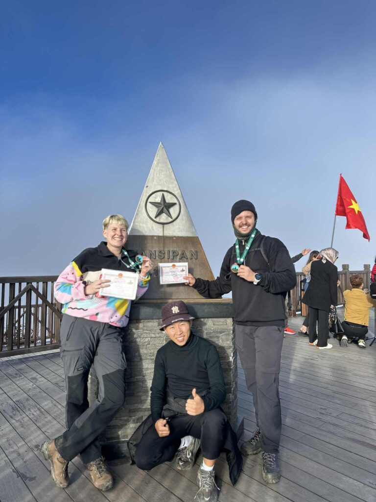 Group of trekkers celebrating at the summit of Fansipan, the highest peak of Indochina.